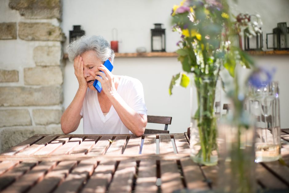 Senior woman looking sadly at her phone while sitting alone