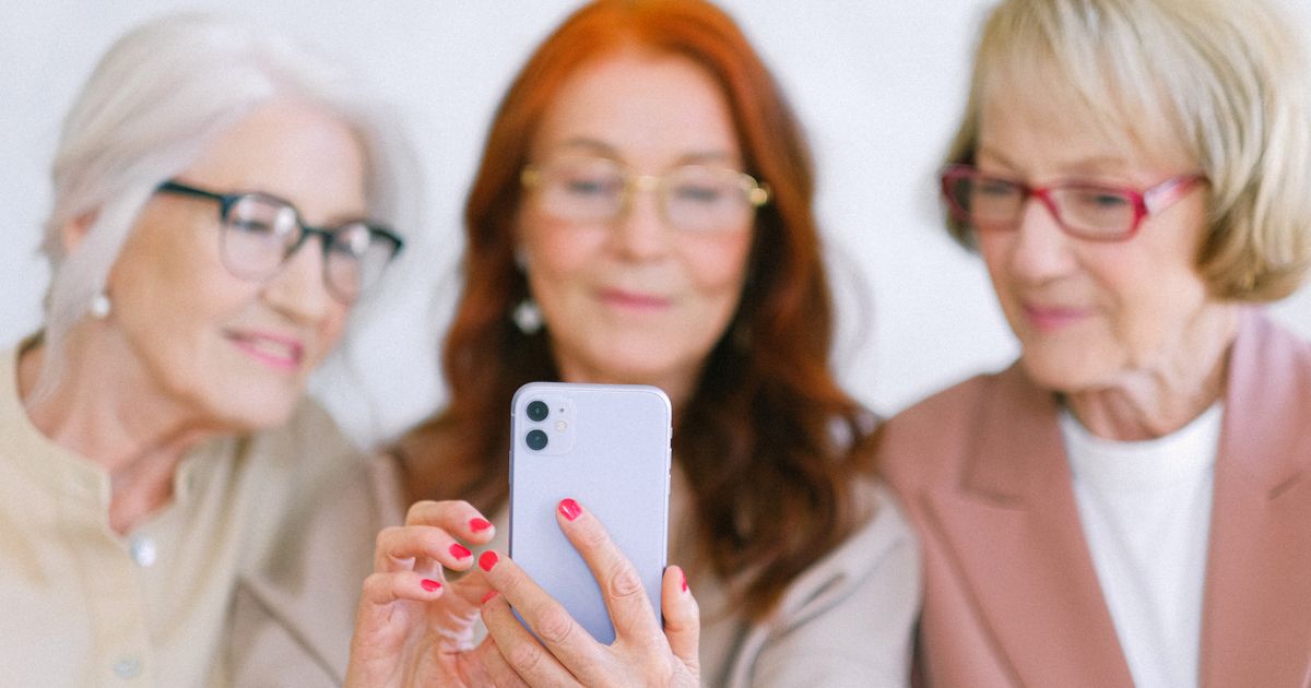 An older adult holding an iPhone at home